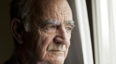 Older man looks out of a window