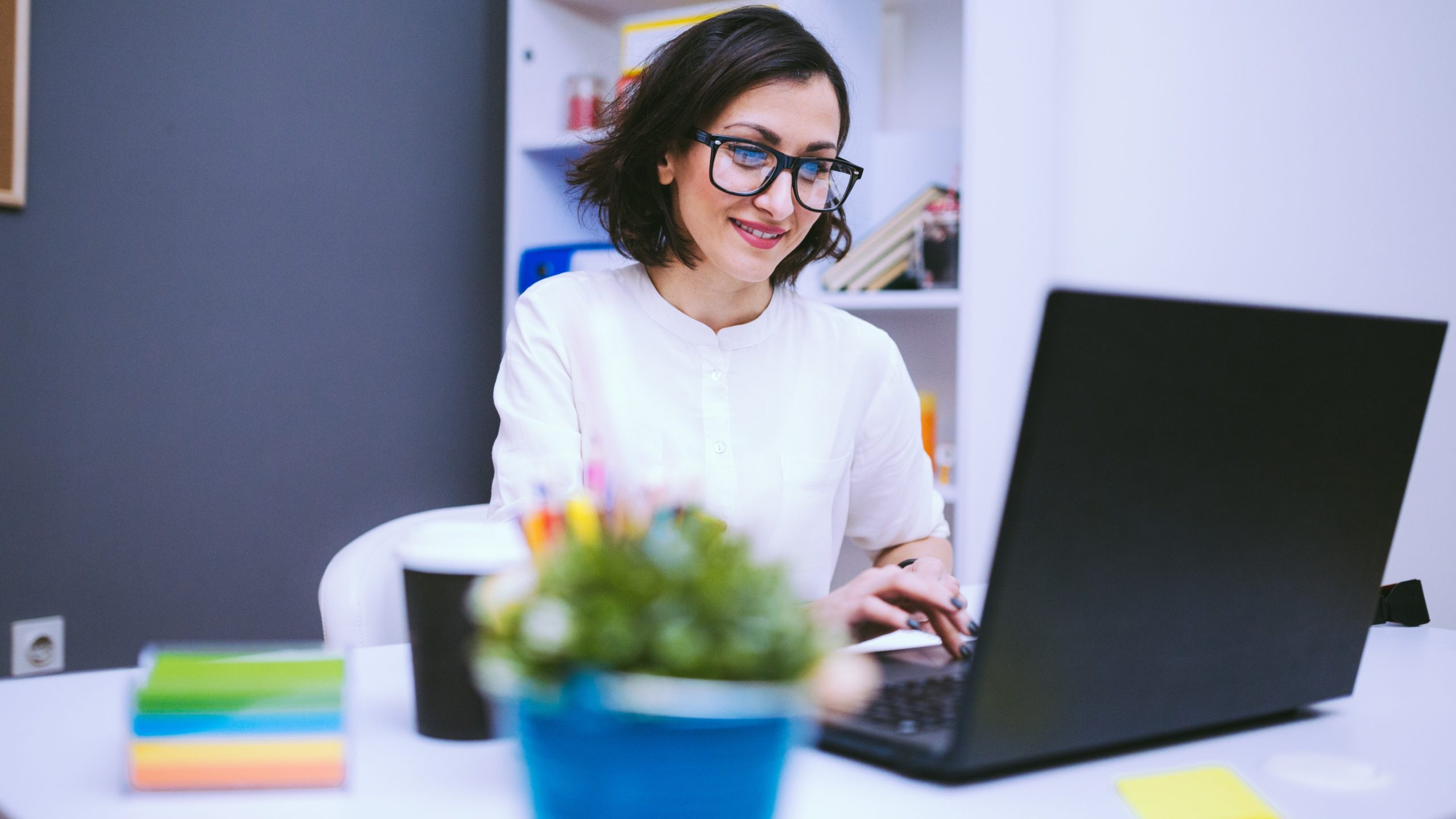 — title missing — Woman sitting at desk using laptop in dental office.