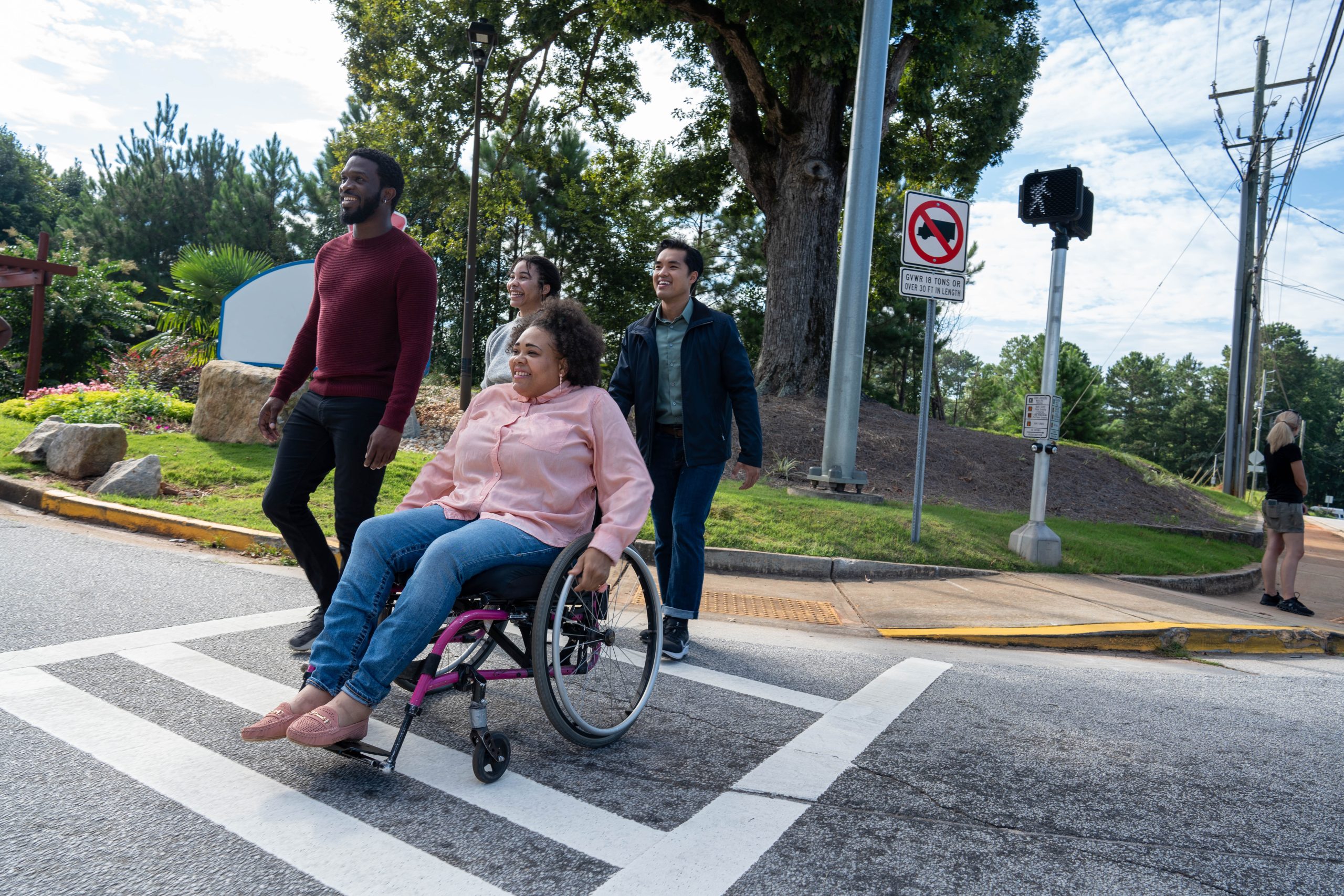 A group of adults walking across the street, using a crosswalk. A group of adults walking across the street, using a crosswalk.